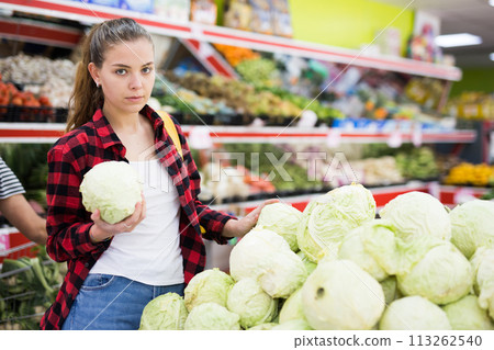 Shopper girl picks out a cabbage near the counter Shopper girl picks out a cabbage near the counter 113262540