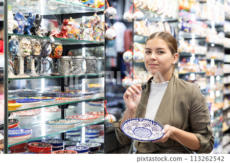 Young woman chooses souvenir dishes in souvenir shop 113262542