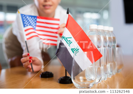 Preparing for business presentation - secretary places flags of Iraq and USA on negotiating table 113262546