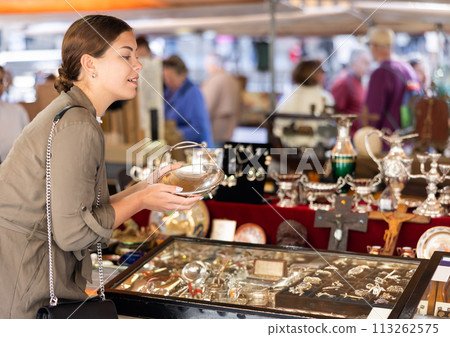 Young woman looking at antique basket at flea market 113262575