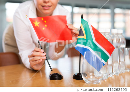 Blurry girl set midget flags of South Africa and China before international negotiations 113262593