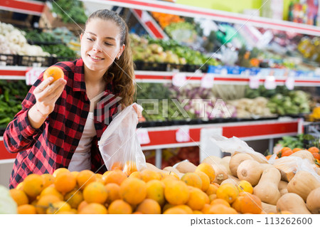 Portrait of young woman buying tangerines at grocery store Portrait of young woman buying tangerines at grocery store 113262600