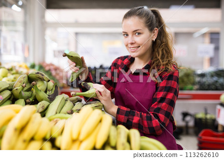 Portrait of a positive young saleswoman checking bananas on the counter Portrait of a positive young saleswoman checking bananas on the counter 113262610