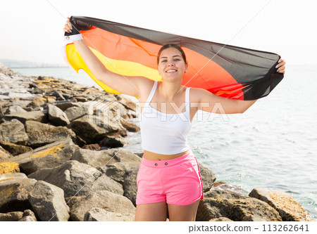 Happy woman on sea beach with Germany flag on sunny day 113262641