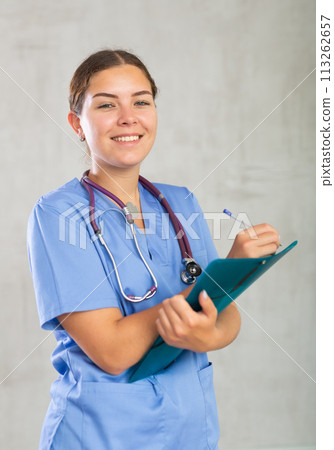 Young woman in medical uniform making notes Young woman in medical uniform making notes 113262657