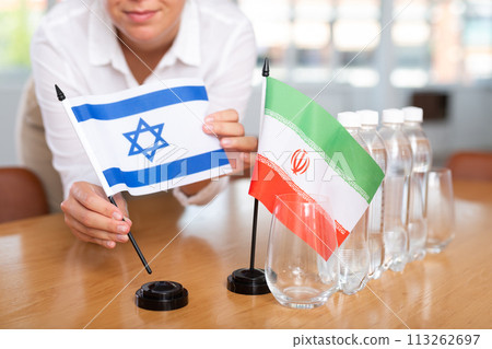 Little flag of Iran on table and flag of Israel put next to it by young woman Little flag of Iran on table and flag of Israel put next to it by young woman 113262697