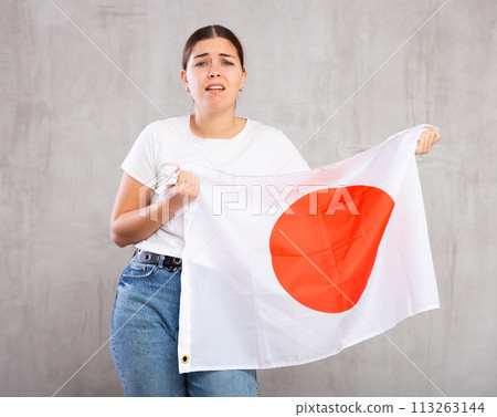 Irritated girl stands with flag of Japan. Isolated on gray background 113263144