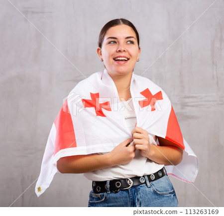 Joyous young woman holding Georgia flag against unicoloured background 113263169
