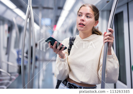 Portrait of a pensive girl with a mobile phone on a subway train 113263385