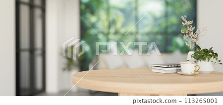 A space for display products on a minimalist round wooden table in a contemporary white living room. A space for display products on a minimalist round wooden table in a contemporary white living room. 113265001