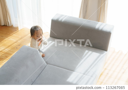 Little girl walking around the sofa 113267085