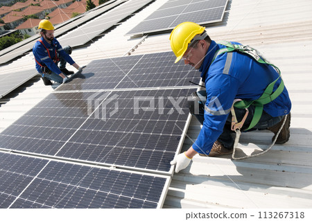 Engineers install solar cells on the roof of factory 113267318