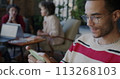 Joyful African American man playing video game with smartphone relaxing in work break in coworking office. Gaming and mobile application concept. 113268103