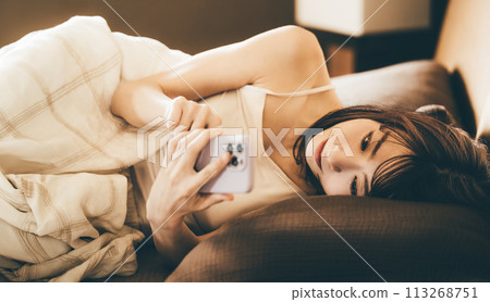 A woman using a smartphone in bed A woman using a smartphone in bed 113268751
