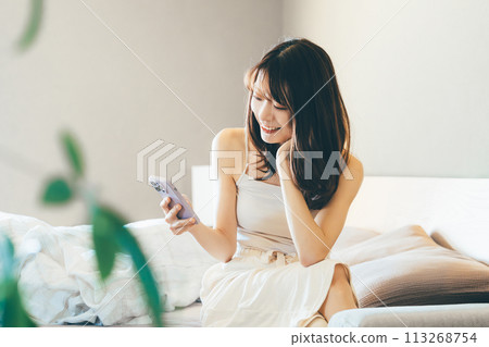 Smiling woman using smartphone in bed 113268754
