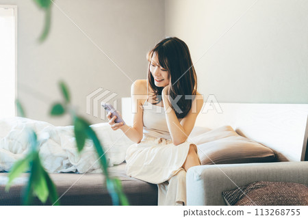 Smiling woman using smartphone in bed Smiling woman using smartphone in bed 113268755