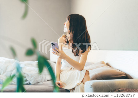 Smiling woman using smartphone in bed 113268757
