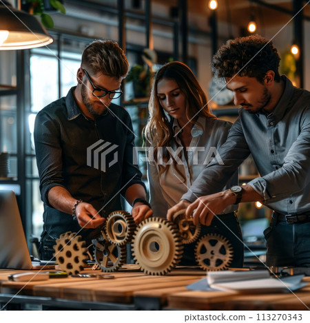 Focused team works together on assembling mechanical gears in a modern office setting 113270343