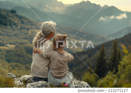 grandmother and granddaughter sitting on a mountainside, back view of people having a rest in the fresh air, family values concept 113271117