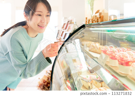 Young woman choosing cake in a shop window Young woman choosing cake in a shop window 113271832