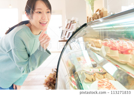 年輕女子在櫥窗裡選擇蛋糕 113271833