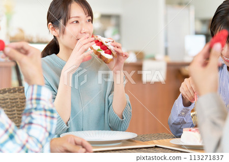 Young women enjoying chatting while eating sweets at a cafe Young women enjoying chatting while eating sweets at a cafe 113271837