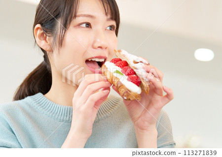 在咖啡館吃草莓糖果的年輕女子 113271839