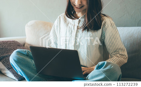Smiling woman using laptop on sofa Smiling woman using laptop on sofa 113272239