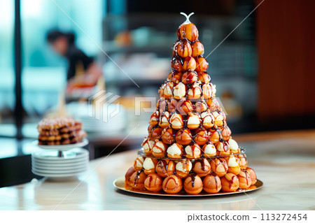 Croquembouche profiterole tower topped with chocolate, layers of choux pastry, filled with cream and topped chocolate 113272454
