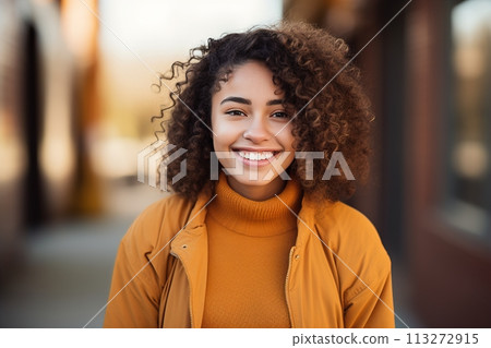 A woman with curly hair is smiling and wearing a yellow jacket 113272915