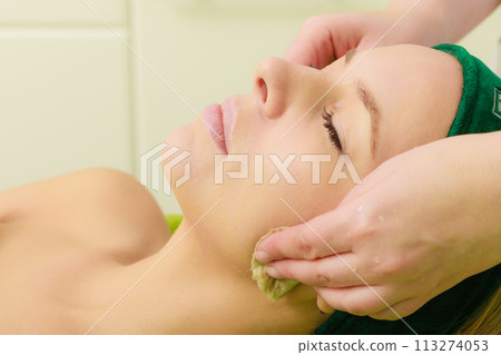 Beautician wiping off green mask on woman 113274053