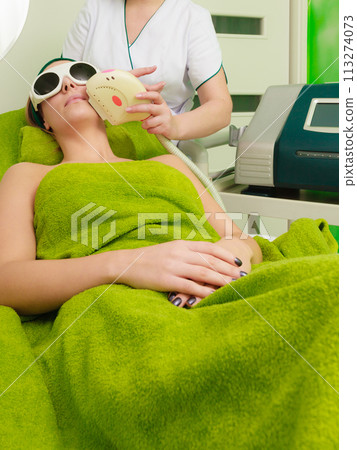 Woman getting laser treatment in beautician 113274073