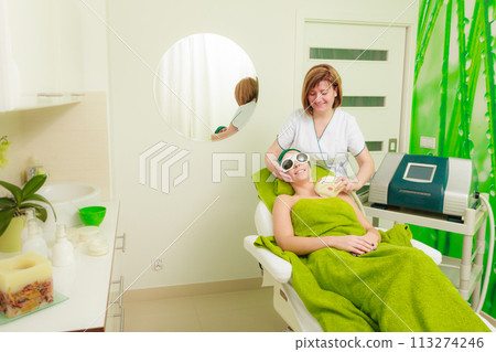 Woman getting laser treatment in beautician Woman getting laser treatment in beautician 113274246