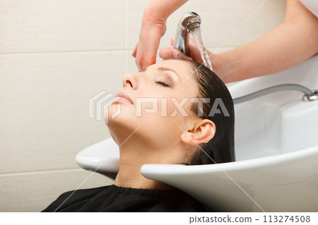 Hairdresser washing her woman customer hair Hairdresser washing her woman customer hair 113274508