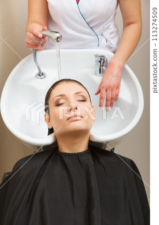 Hairdresser washing her woman customer hair Hairdresser washing her woman customer hair 113274509