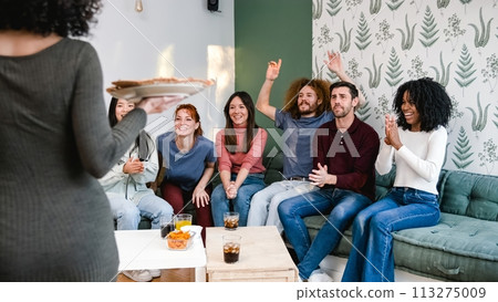 Diverse friends cheering up for anonymous woman bringing pizzas during party at home Diverse friends cheering up for anonymous woman bringing pizzas during party at home 113275009