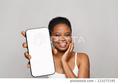 Lovely healthy woman holding smartphone with white empty blank screen display on gray studio Lovely healthy woman holding smartphone with white empty blank screen display on gray studio 113275195