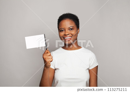 Attractive young African American woman holding empty flag banner in her hand on gray background Attractive young African American woman holding empty flag banner in her hand on gray background 113275211