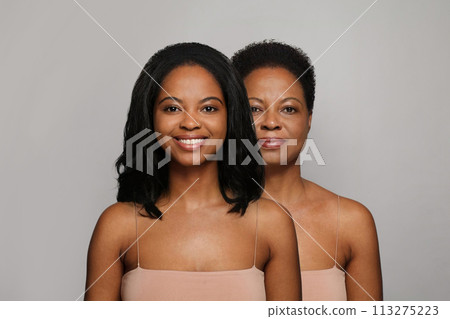 Charming young and mature woman smiling on gray background. Aging, cosmetology, plastic surgery Charming young and mature woman smiling on gray background. Aging, cosmetology, plastic surgery 113275223