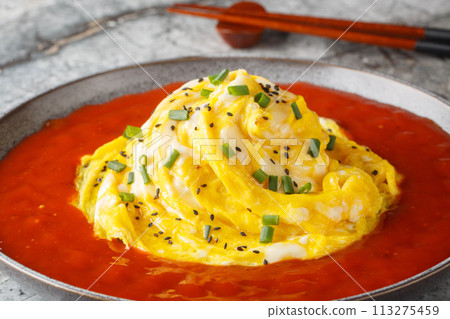Swirl omelette tornado with fried rice and hot pepper sauce close-up in a plate. Horizontal 113275459
