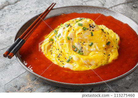 Asian swirl omelette tornado with fried rice and hot sauce close-up in a plate. Horizontal 113275460
