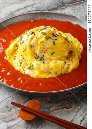 Korean tornado omelette over fried rice and hot sauce closeup on the plate. Vertical 113275463