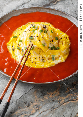 Korean tornado omelette on top of rice and hot sauce around it close-up in a plate. Vertical 113275464