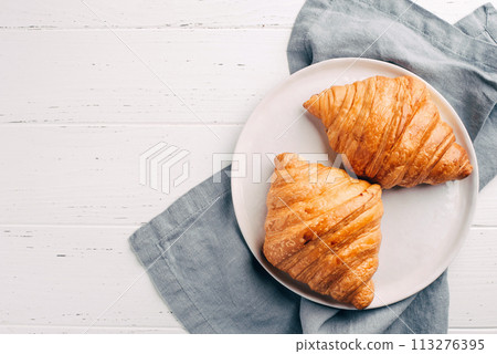 Plate with two fresh croissants on white table. Plate with two fresh croissants on white table. 113276395