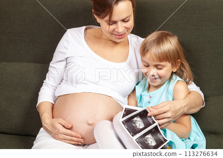 Expectant Mother and Daughter Looking at Ultrasound 113276634