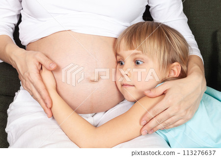 Wonderstruck Child Embracing Expectant Mothers Belly 113276637