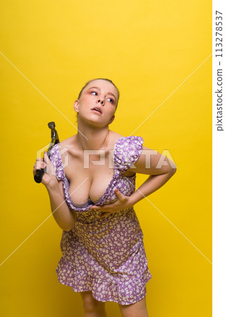 Beautiful seductive female holding hammer, isolated on yellow and red Beautiful seductive female holding hammer, isolated on yellow and red 113278537
