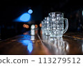 A row of glasses on a wooden table with a blue background 113279512
