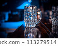 A glass mug is sitting on a wooden bar counter 113279514