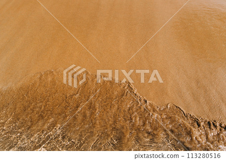 sandy beach with waves rolling in, creating a beautiful natural background. beige sand contrasts with ocean waves. concept for perfumes, smells, heat, freshness, coolness and other associations 113280516